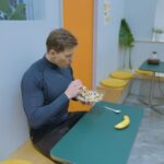 momak sedi za stolom u teretani i jede spremljen obrok nakon treninga