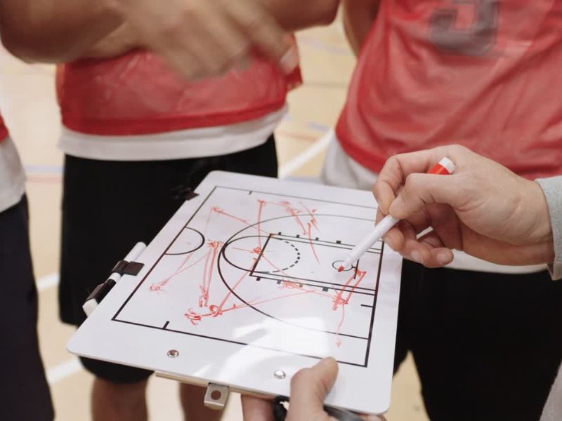 prikaz košarkaškog trenera koji crta po tabli i pravi strategiju za dalju utakmicu