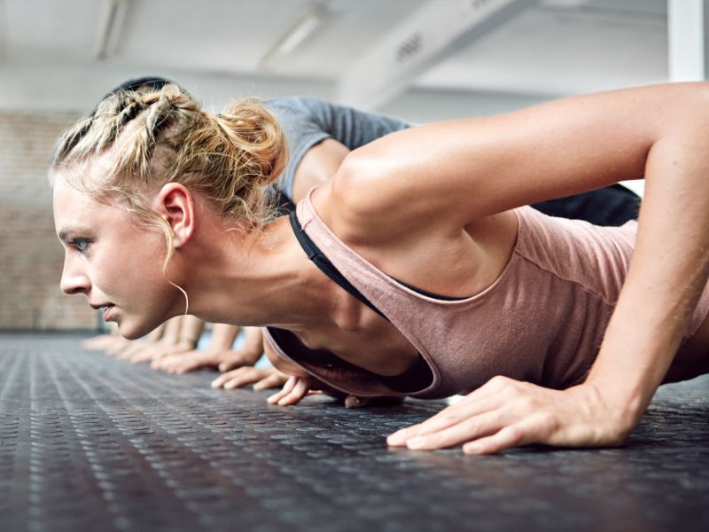 devojka radi sklekove na grupnom treningu