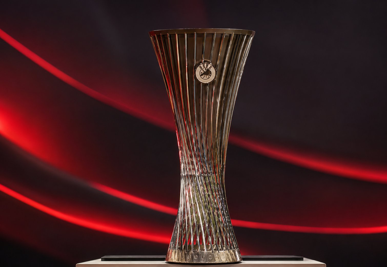 Trofej UEFA Lige konferencija na postolju, osvetljen crvenim linijama na tamnoj pozadini.